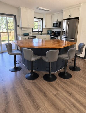 A modern kitchen with a central island, bar stools, and stainless steel appliances.