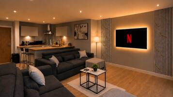 Ein modernes Wohnzimmer mit einer Couch, einem Couchtisch und einem an der Wand montierten Fernseher.
