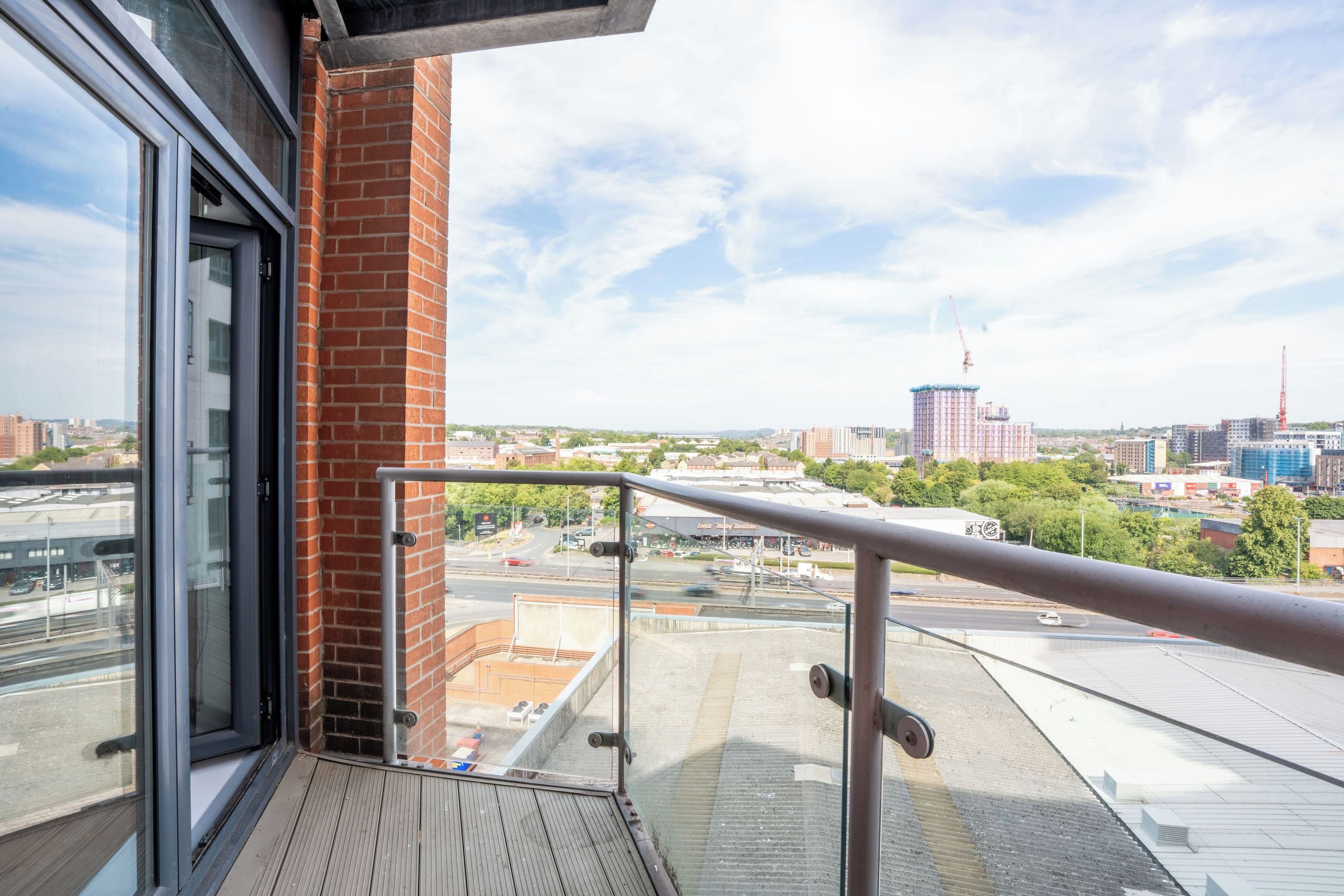 Ein Balkon mit Metallgeländer, einer Ziegelwand und einer Glastür.