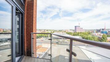Ein Balkon mit Metallgeländer, einer Ziegelwand und einer Glastür.