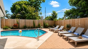 A backyard with a swimming pool, lounge chairs, and a wooden fence. - Sunset Paradaise in Fort Lauderdale (Fort Lauderdale)