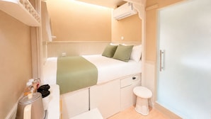 Camera d'albergo compatta con un letto a castello, un bagno piccolo e un armadio.