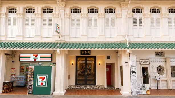 Un edificio tradizionale con un negozio 7-Eleven, un caffè e una porta con un'insegna in lingua straniera.