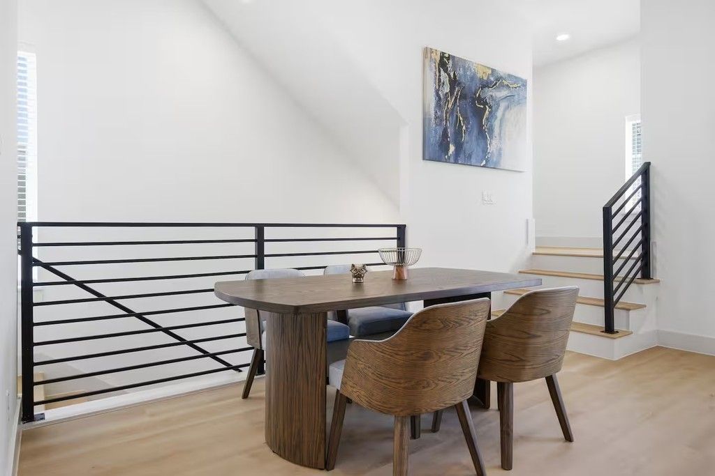 Un coin repas avec une table et des chaises, un tableau au mur et un escalier.