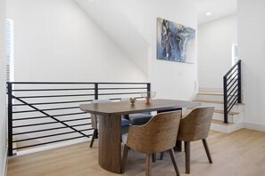 A dining area with a table and chairs, a painting on the wall, and a staircase. - Grand 3BR/3.5BA w/2-Car Garage mins to Downtown (Houston)