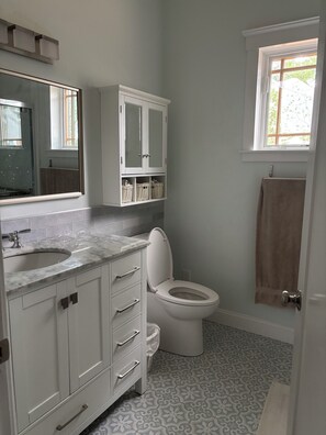 Een badkamer met toilet, wastafel, spiegel en een kast met manden.
