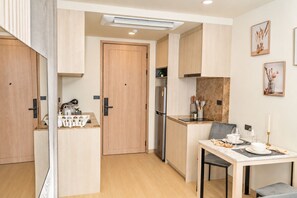 Eine kleine Küche mit Holzschränken, einem integrierten Kühlschrank und einer Essecke mit Tisch für zwei Personen.