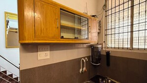 Una cocina con armarios de madera, un lavamanos de acero inoxidable y una ventana con barrotes.