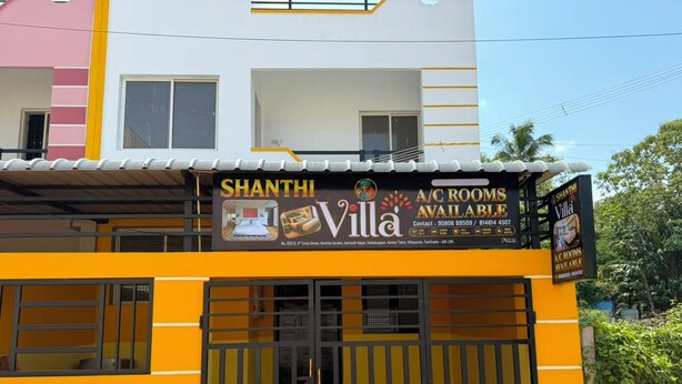 Un edificio de dos pisos con un cartel que anuncia 'Shanthini Villa' y 'habitaciones con aire acondicionado disponibles'.