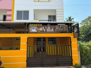 Edificio de dos pisos con un letrero que anuncia 'Shanthini Villa' y habitaciones disponibles.