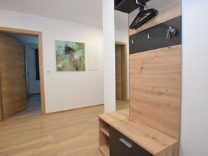 Ein Zimmer mit Holzboden, einer Bank, einem Wandfahrradständer und einer Tür zu einem weiteren Raum.