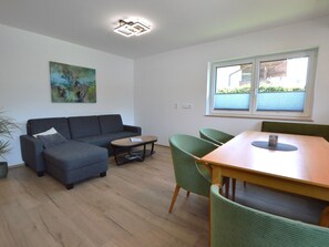 A modern living room with a sofa, coffee table, and dining table with chairs. - Modern, spacious apartment by the leisure lake (Uttendorf)