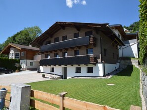 Ein mehrstöckiges Gebäude mit Balkonen, einem gepflegten Rasen und blauem Himmel.