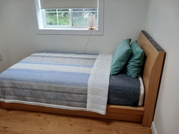 A single bed with a striped bedspread, two pillows, and a bedside lamp.
