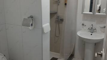 A bathroom with a toilet, a shower, and a sink.