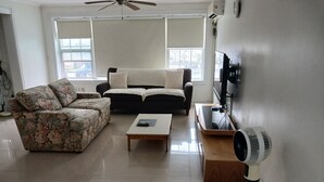 Una sala de estar con sofá, mesa de centro, televisor y ventilador.