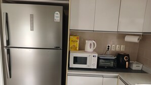 Una cocina con un refrigerador de acero inoxidable, un microondas, un tostador y una tetera sobre la encimera.