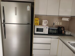 Eine Küche mit einem Edelstahl-Kühlschrank, einer Mikrowelle, einem Toaster und einem Wasserkocher auf der Arbeitsfläche.