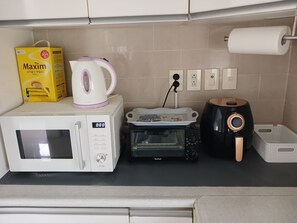 A kitchen with a microwave, toaster, kettle, and a box of Maxim tissues.