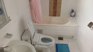Un baño con inodoro, lavamanos, bañera y cortina de ducha.