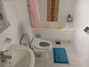 Ein Badezimmer mit Toilette, Waschbecken, Badewanne und Duschvorhang.