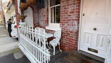 A building with a white door marked with the number 10, a brick facade, and a white picket fence.