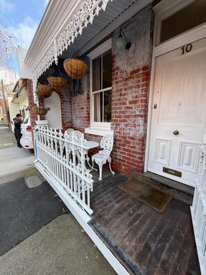 A building with a white door marked with the number 10, a brick facade, and a white picket fence.