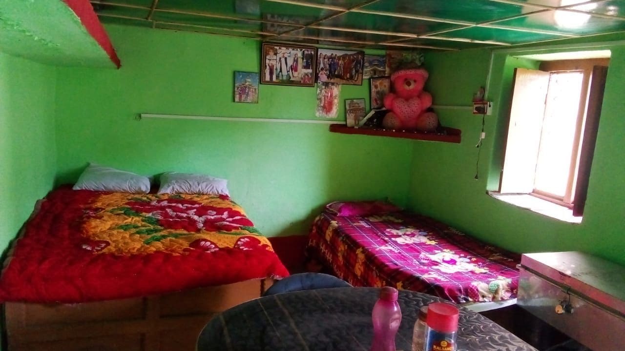 A room with two beds, a small table, and a window.