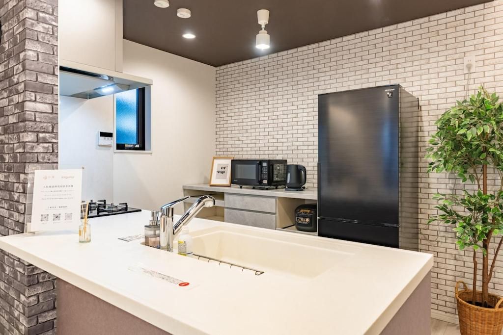 A modern kitchen with a white countertop, black appliances, and a brick wall backsplash.