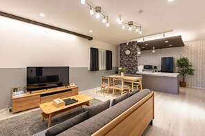 Una sala moderna con televisor de pantalla plana, sofá, mesa de centro y comedor.
