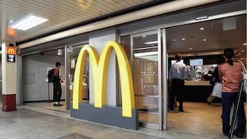 A McDonald's restaurant with a large yellow logo, a glass entrance, and a person entering.