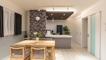 A modern kitchen with a central island, a dining area with a wooden table and chairs, and a living space with a sofa and a coffee table.