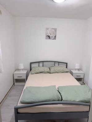 Une chambre à coucher avec un lit, deux tables de chevet, un tableau accroché au mur et un luminaire au plafond.