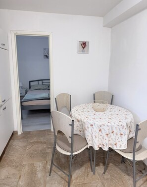A small, well-lit room with a bed, a round table with chairs, and a tiled floor. - Apartma Celeste Welcome to a cozy and comfortable apartment in Isola. (Isola)