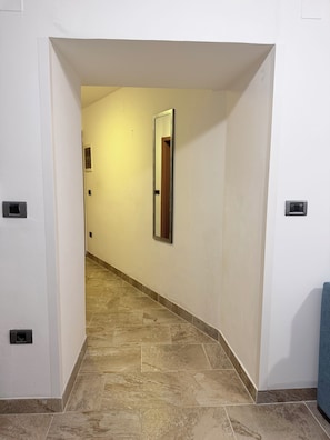 A hallway with a tiled floor, a door frame, and a wall-mounted light fixture. - Apartma Celeste Welcome to a cozy and comfortable apartment in Isola. (Isola)