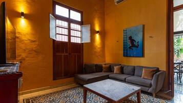 A room with a sofa, a coffee table, a wall-mounted TV, a window with a view, and a painting.