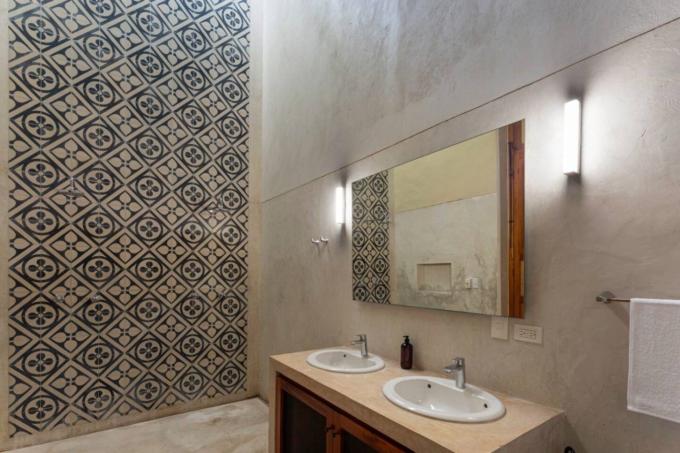 A bathroom with two sinks, a mirror, and patterned tile walls.