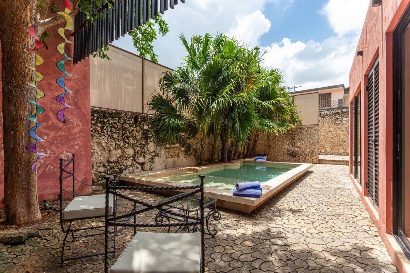 A private outdoor pool area with a stone wall, a bench, and a table.