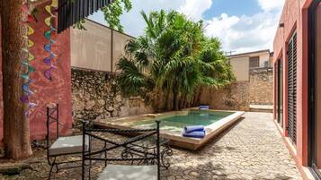 A private outdoor pool area with a stone wall, a bench, and a table.