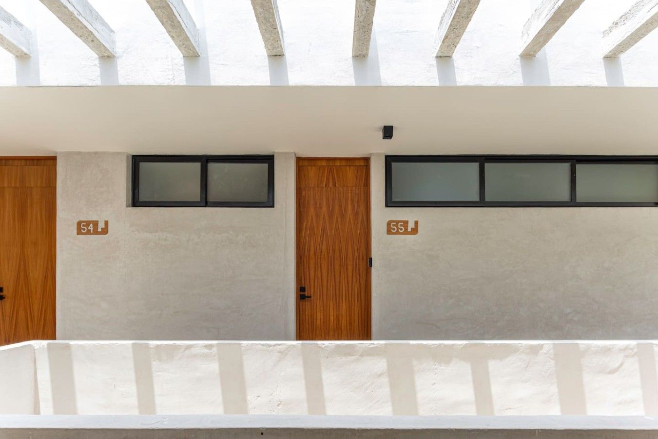 Un edificio con dos puertas, las cuales llevan las etiquetas 54 y 55, cada una con un ventanal encima.