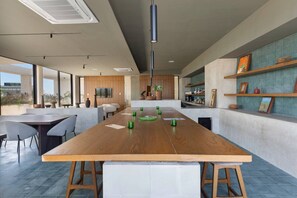 Cozinha moderna com ilha central, espaço para bar e área de refeições com cadeiras.