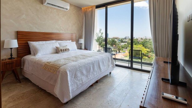 Ein Hotelzimmer mit einem großen Bett, einem Fernseher und einem Balkon mit Blick.