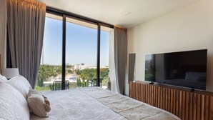 Ein modernes Hotelzimmer mit einem großen Bett, einem Flachbildfernseher und einem Balkon mit Blick auf die Stadt.