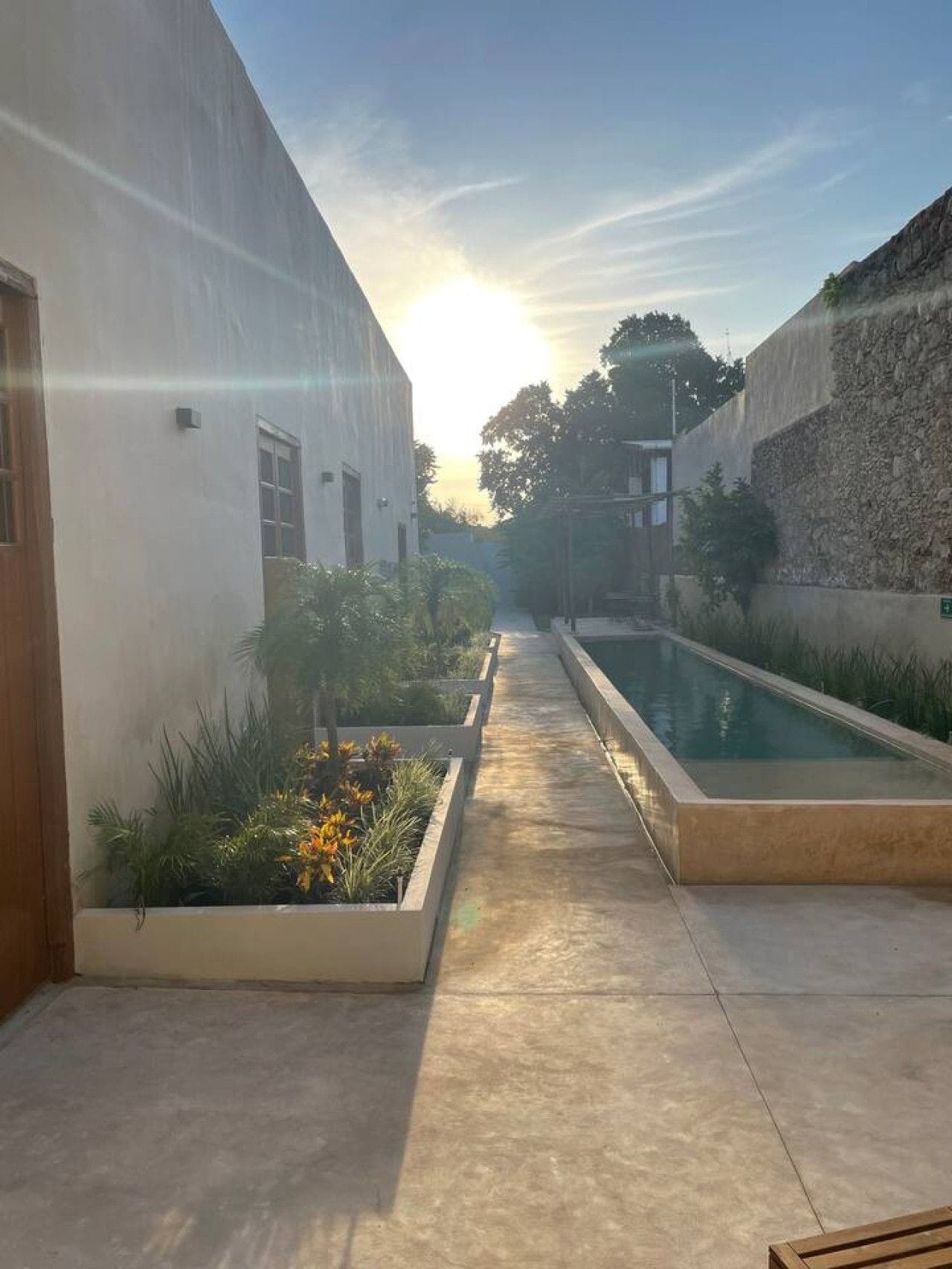 Ein Innenhof mit Pool, einem Weg und Gebäuden mit einer Steinmauer.