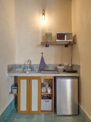 A compact kitchen with a built-in microwave, a small refrigerator, and a shelf with a microwave on top. - Colonial House w/5 studios + pool • A+ Location (Merida)