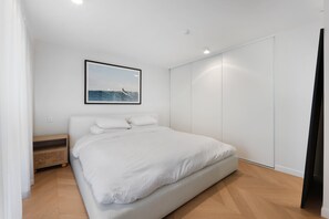 Ein Schlafzimmer mit einem Bett, einem Nachttisch, einem Wandbild und einem Kleiderschrank.