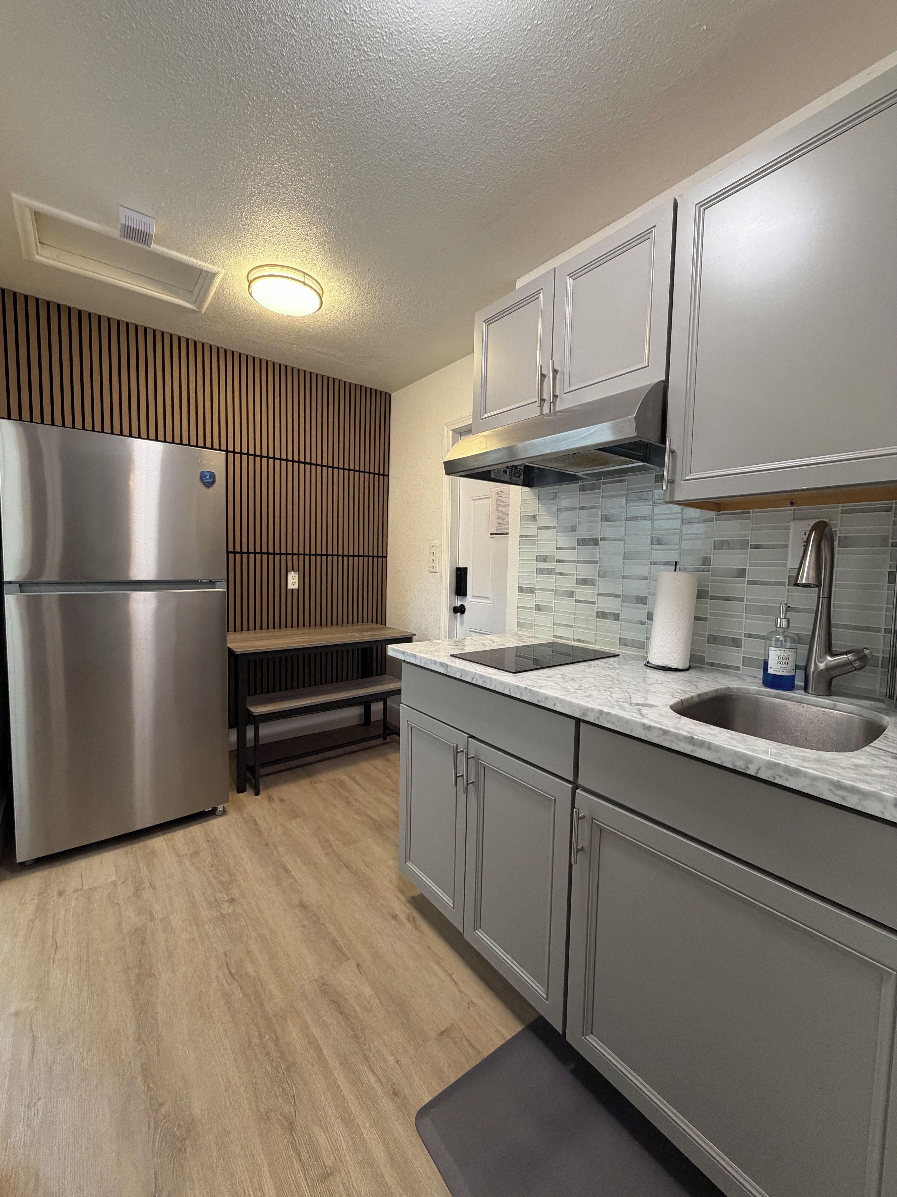 A modern kitchen with a built-in refrigerator, a sink with a faucet, and a wooden bench.