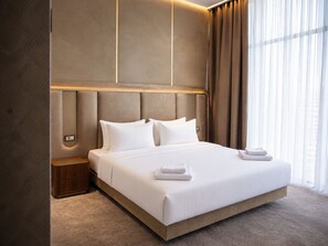 A modern hotel room with a large bed, a nightstand, and a window with curtains. - The Arte Hotel (Yerevan)