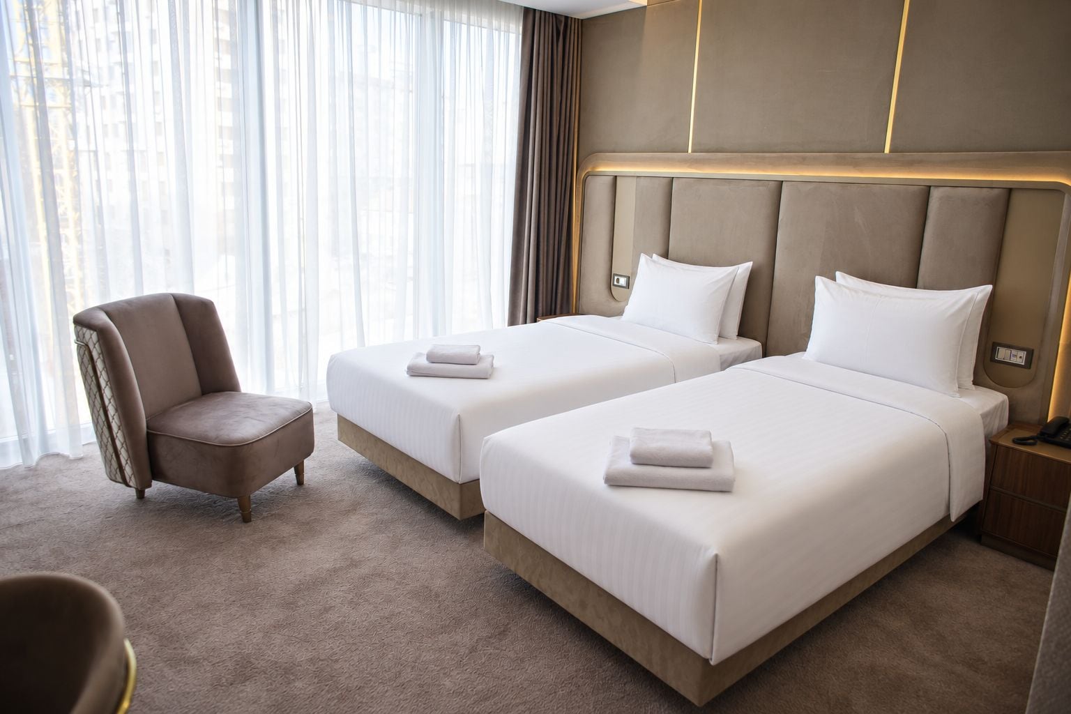 Een hotelkamer met twee bedden, een stoel en een nachtkastje.