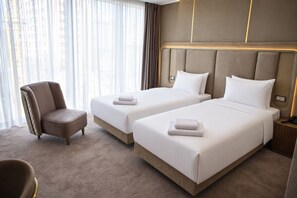 A hotel room with two beds, a chair, and a nightstand.
